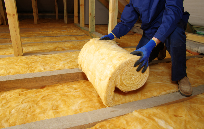 person installing rolls of insulation to an attic floor